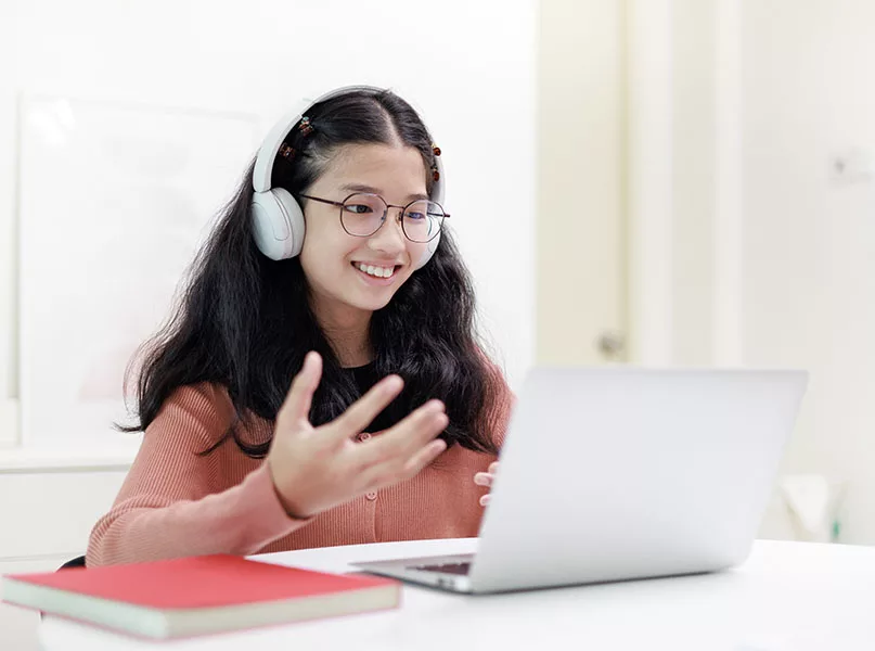 Young girl sitting at desk, wearing headphones