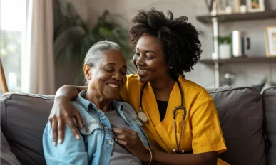 Smiling young female nurse caregiver assisting senior woman